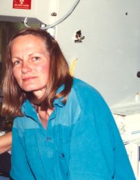 Uli Munderloh, 1980's - shoulder length brown hair, blue long sleeve button down, sitting in a lab