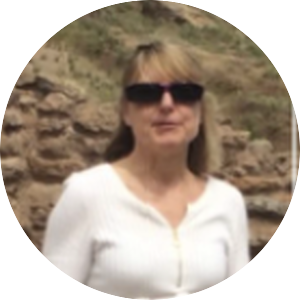 Nicole Burkhardt- shoulder length blonde hair, black sunglasses, white shirt, standing outside